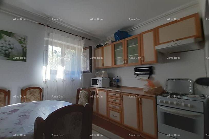 Funktionale Küche mit hellen Holzschränken, Esstisch und Fenster, ausgestattet mit grundlegenden Geräten.