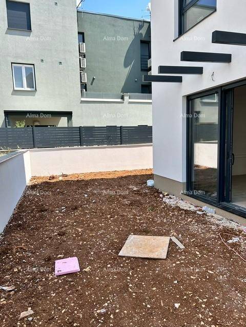 Unfertiger Außenbereich neben dem Neubau mit Erdboden und Blick auf benachbarte Gebäude.