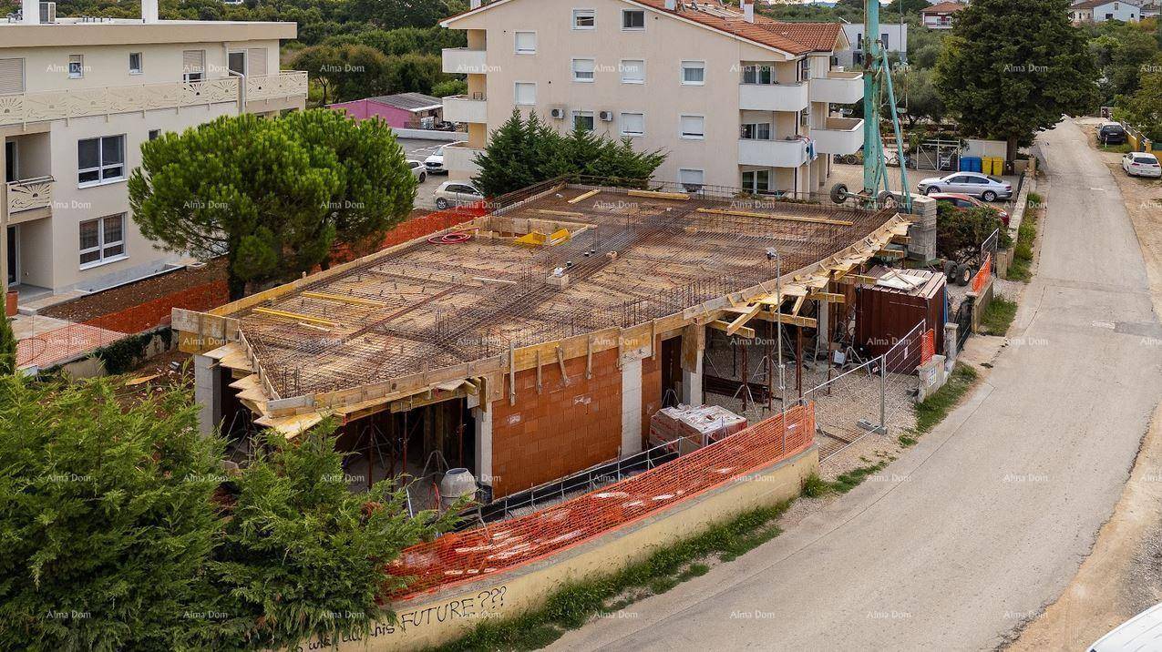 Blick auf die Baustelle eines neuen Gebäudes, das sich in der Rohbauphase befindet, mit umliegenden Wohngebäuden.