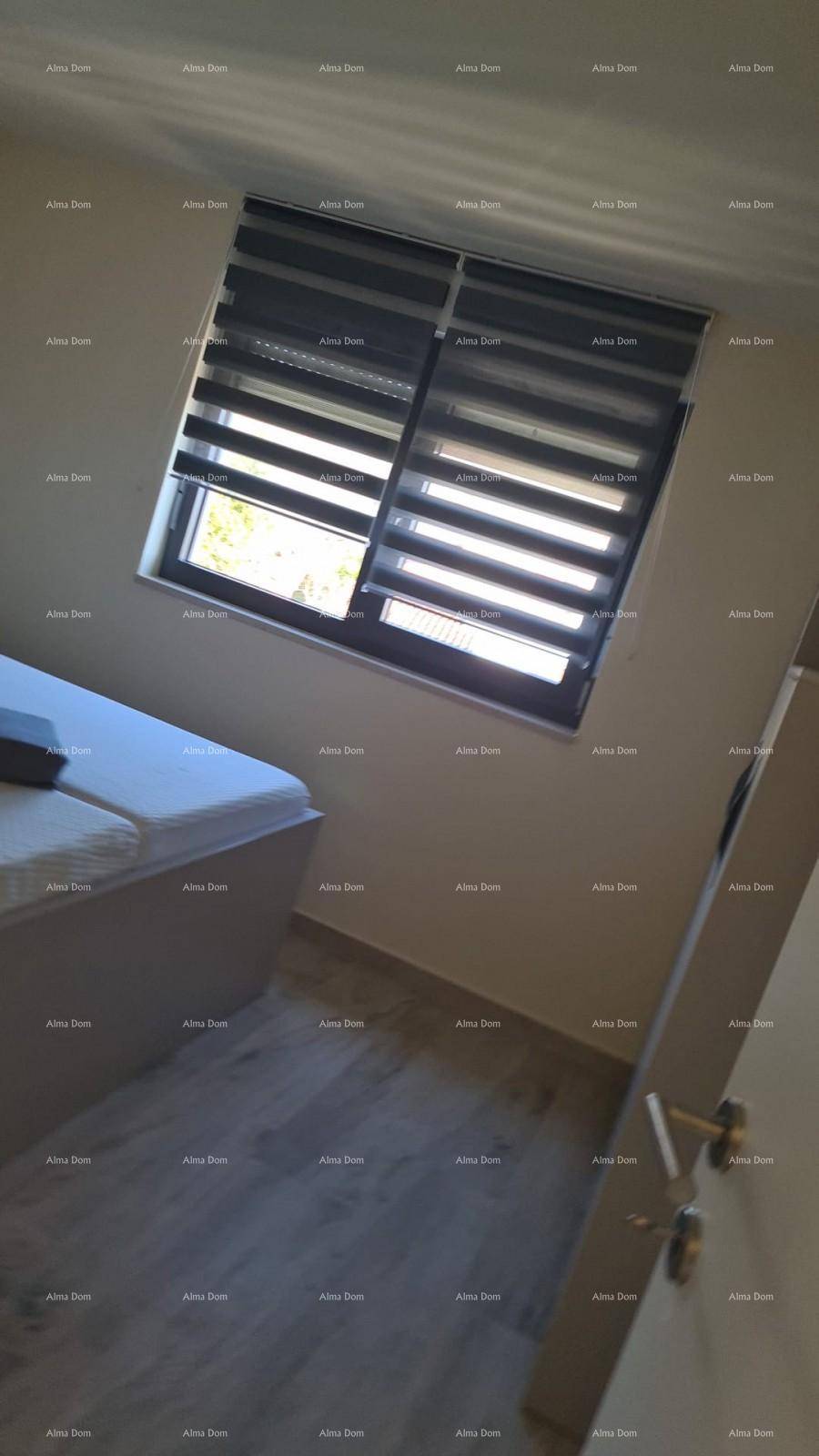 Helles Schlafzimmer mit Einzelbett, Laminatboden und Fenster mit Jalousien.