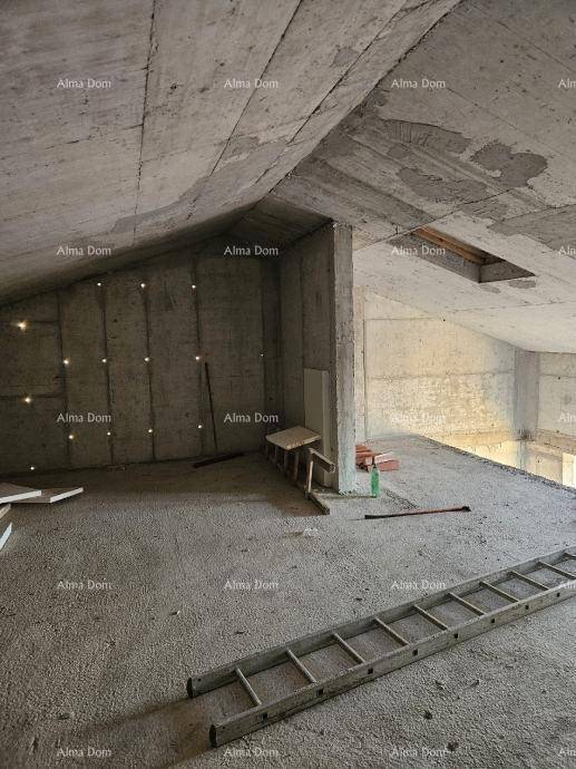 Dachgeschoss im Rohbau mit schrägen Betonwänden, Betonboden und einer Leiter.