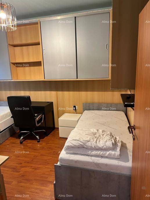 Schlafzimmer mit Einzelbett, Schreibtisch und praktischen Einbauschränken über dem Bett.