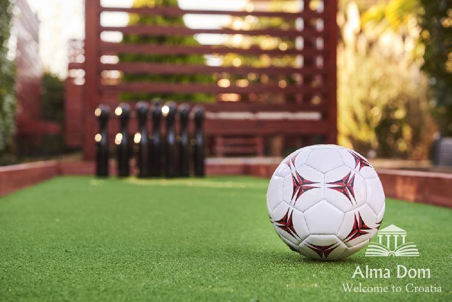 Outdoor-Kegelbahn und Fußball auf Kunstrasen mit Holzpergola im Hintergrund.