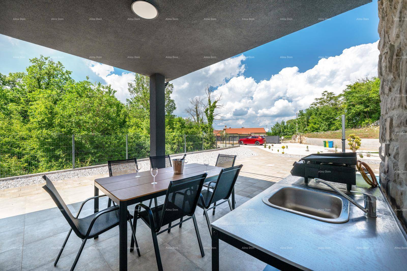 Überdachte Terrasse mit Essbereich und Außenküche, bietet einen weiten Blick ins Grüne.