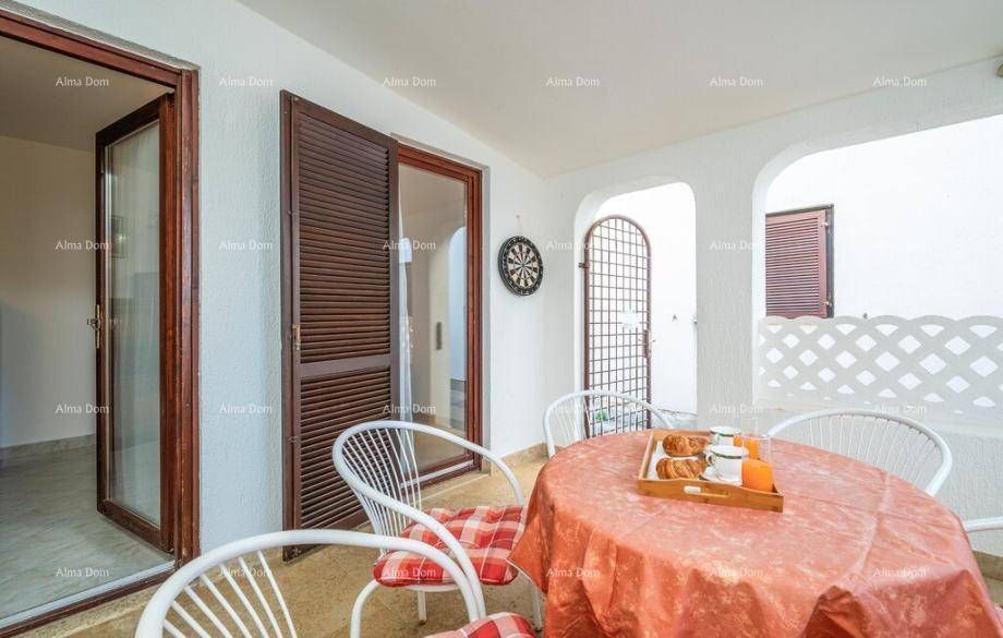 Helle Terrasse mit Esstisch, Stühlen und einem Dartboard an der Wand für Unterhaltung.