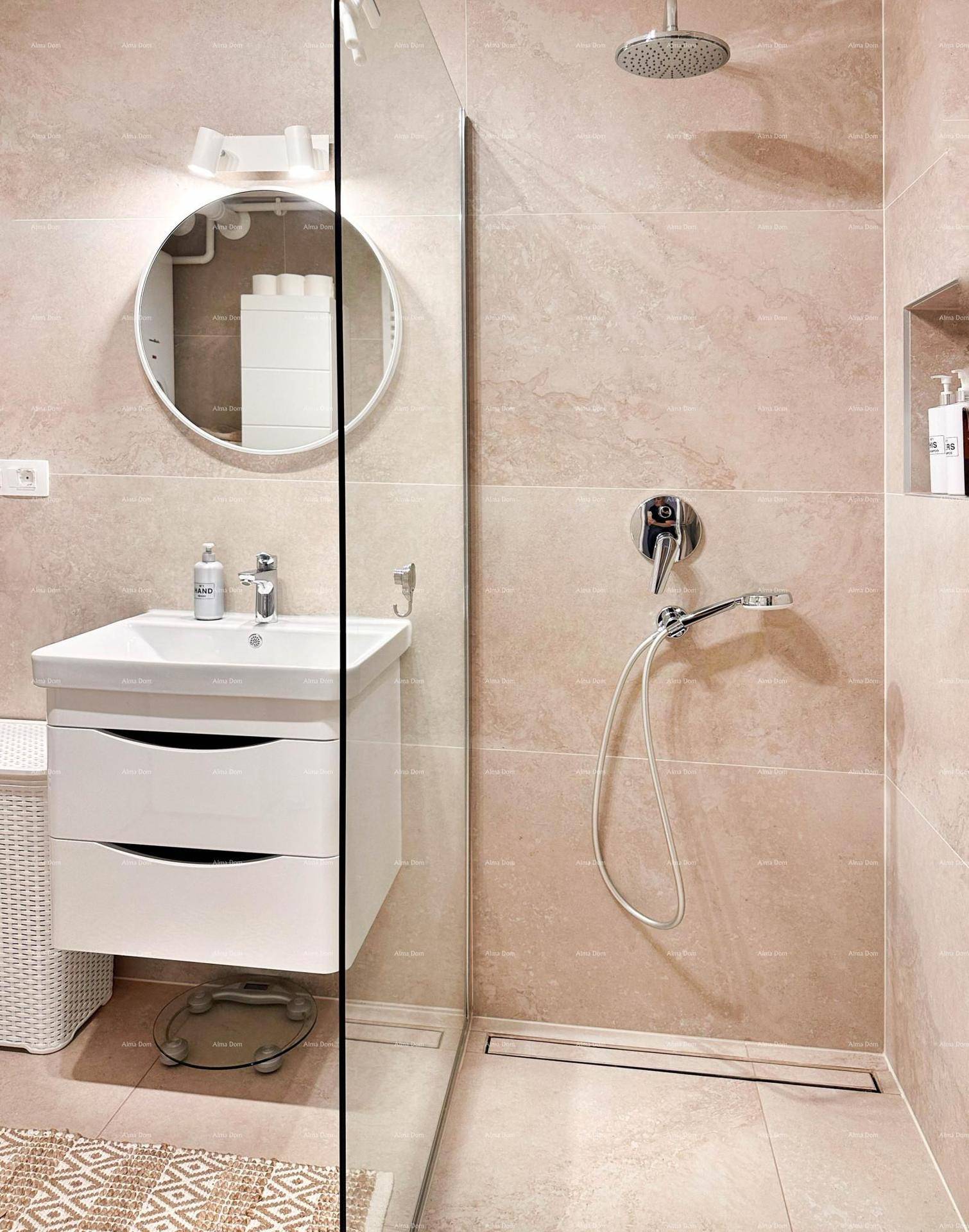 Modernes Badezimmer mit ebenerdiger Dusche, runden Spiegel und beigen Fliesen.