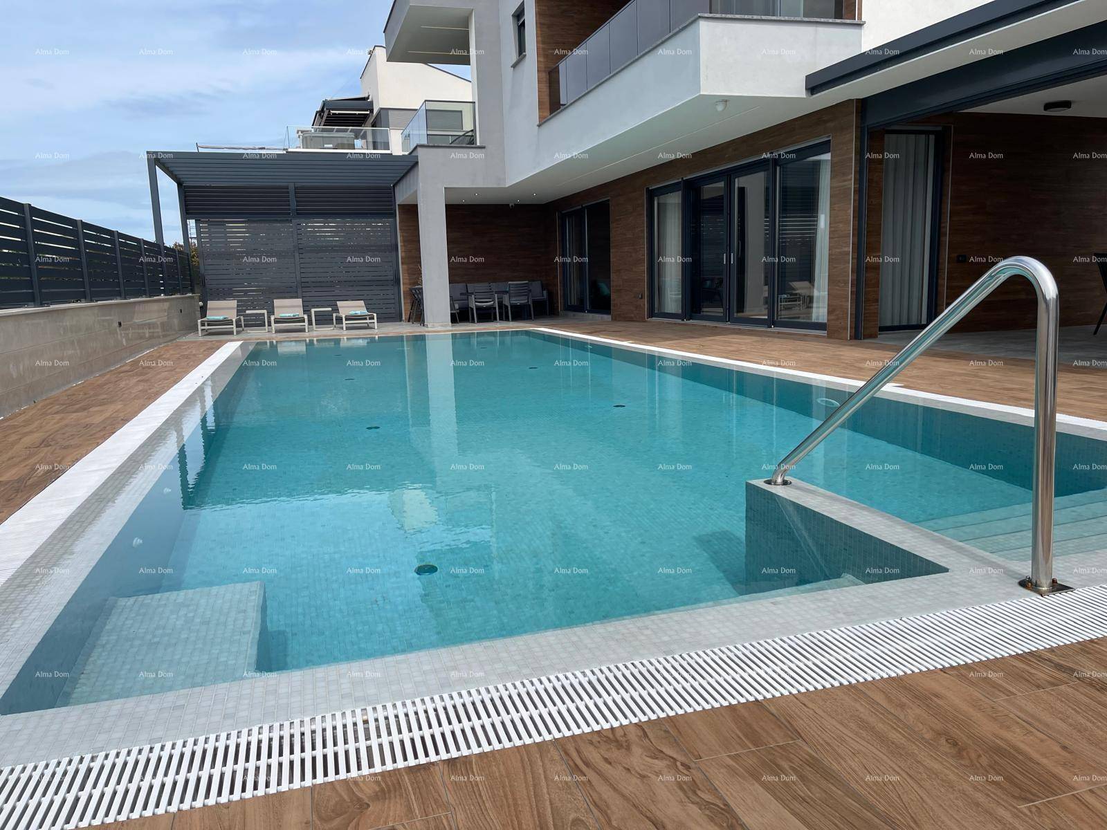 Großer Außenpool mit eleganten Fliesen und Treppenzugang, umgeben von einer Holzterrasse.