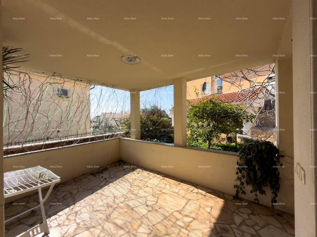 Überdachte Terrasse mit Fliesenboden und Blick auf den Garten.