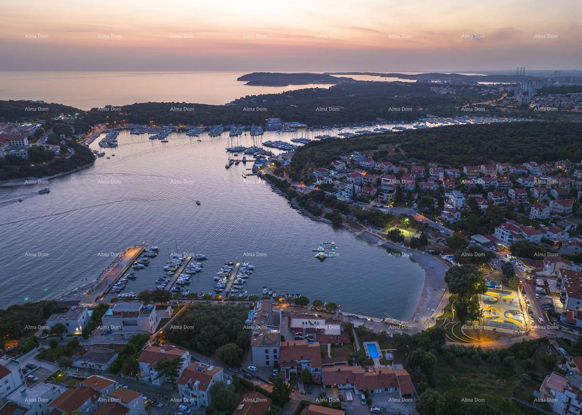 Malerische Luftaufnahme einer Küstenstadt mit beleuchtetem Hafen und Bucht bei Sonnenuntergang.