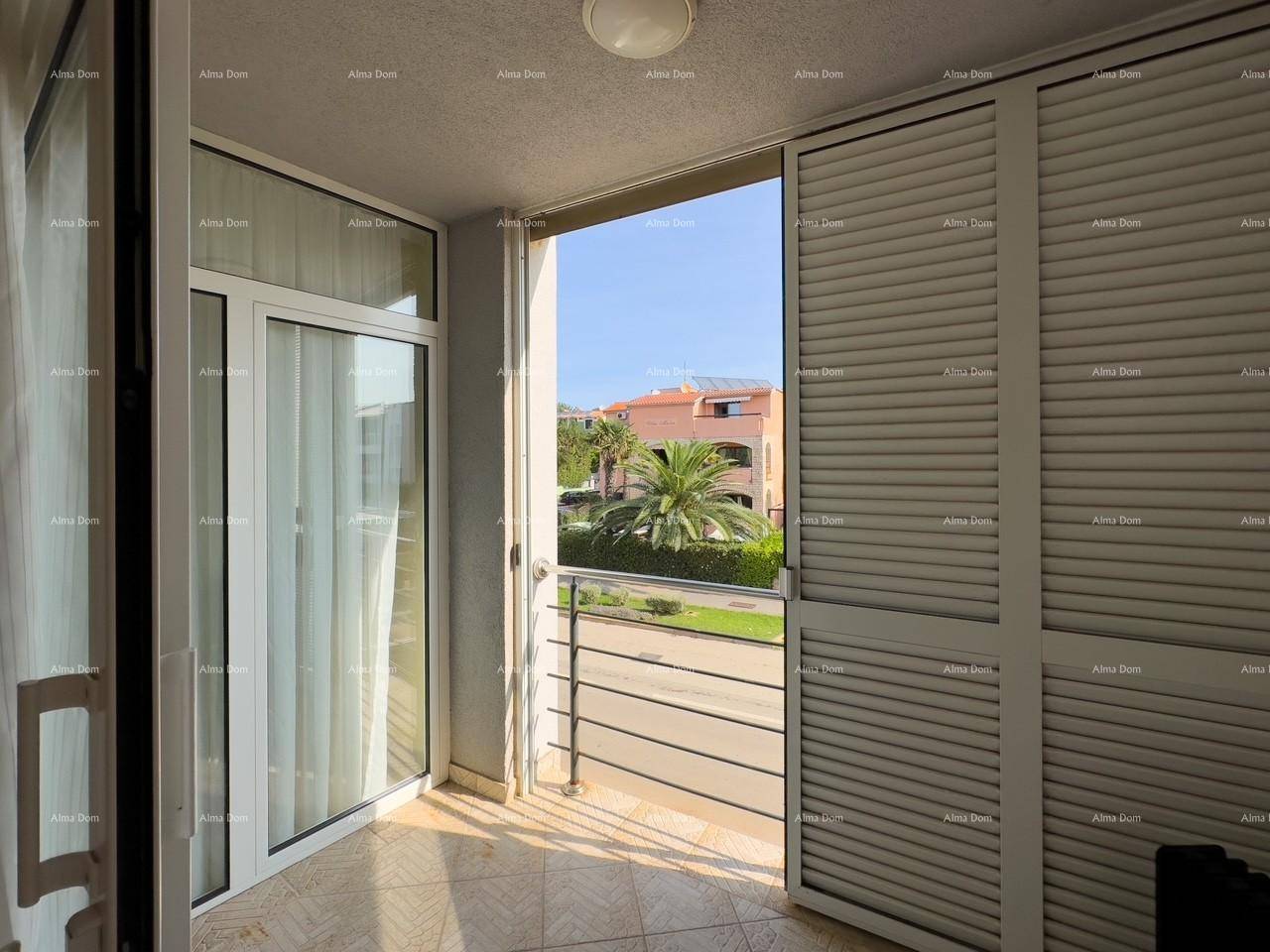 Heller Balkon mit Fensterläden und Blick auf die grüne Umgebung und die Straße.