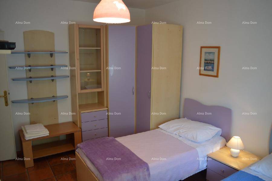 Helles Kinderzimmer mit zwei Einzelbetten, lila Schrank und offenen Regalen für Stauraum.