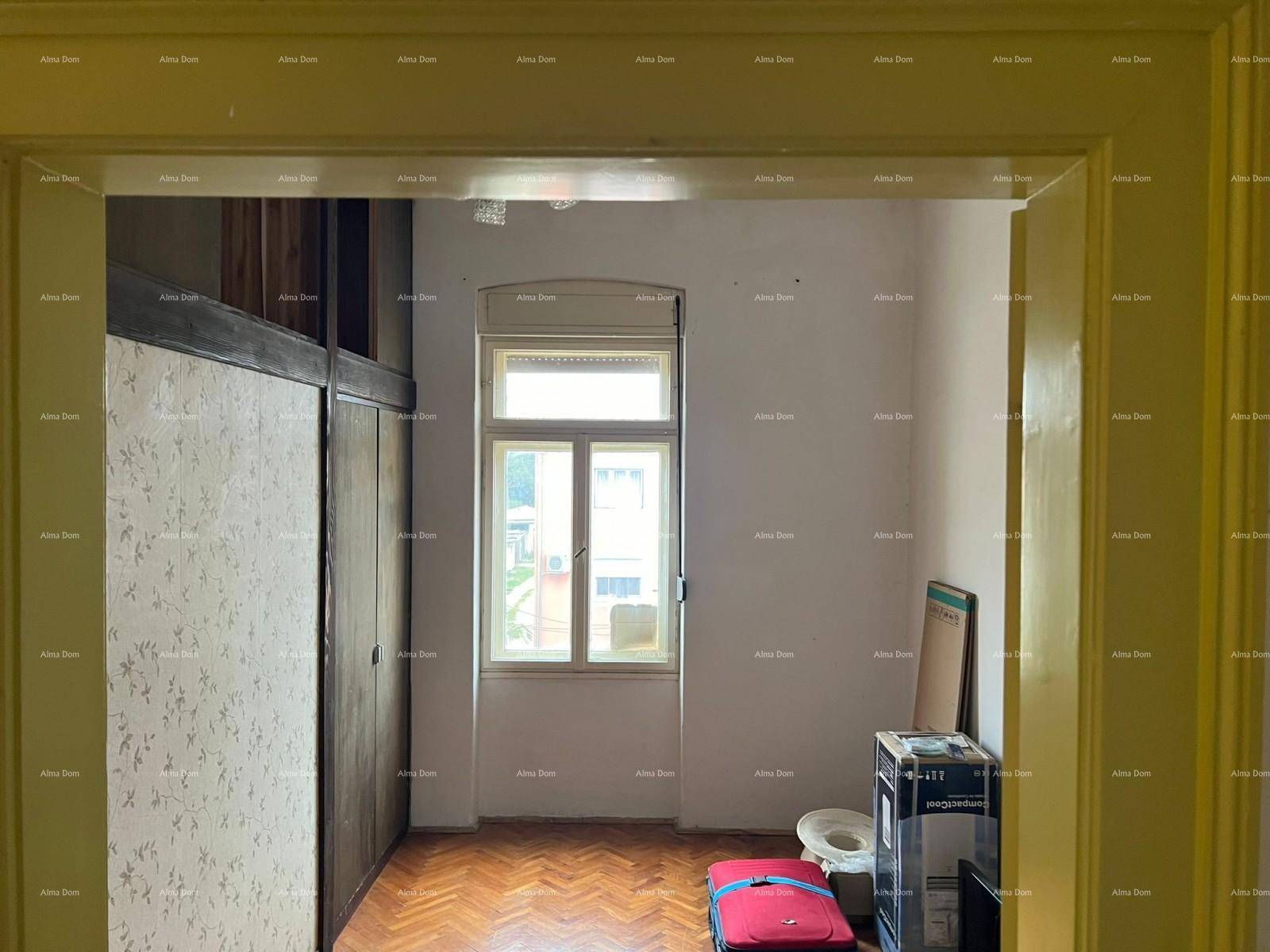 Schlafzimmer mit Fischgrätparkett, einem Fenster und praktischen Einbauschränken aus Holz.