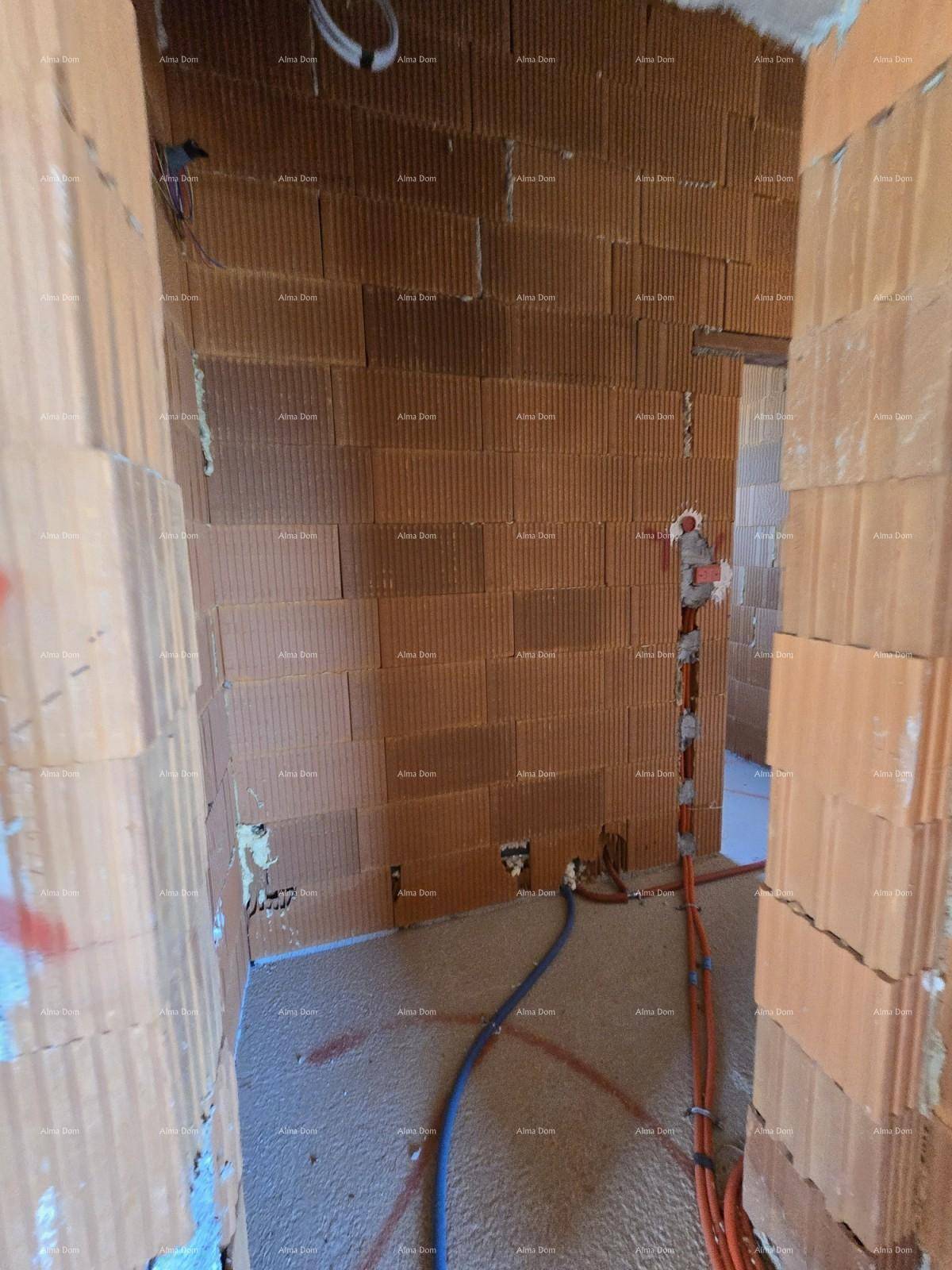 Flur im Rohbau mit unverputzten Ziegelwänden und sichtbaren Elektroinstallationen.