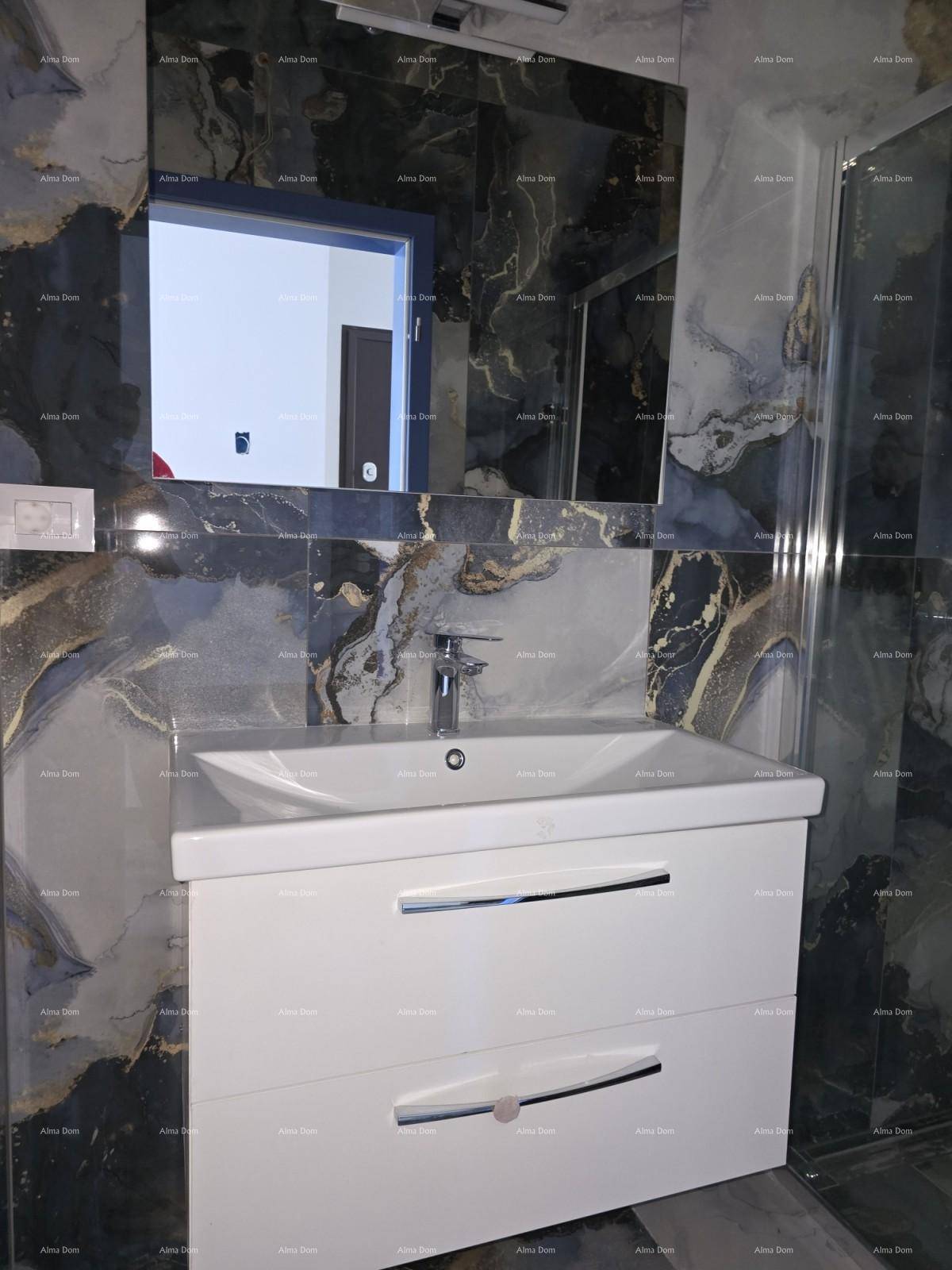Badezimmer mit modernem Waschtisch, großem Spiegel und dunklen Marmorfliesen, die eine elegante Atmosphäre schaffen.