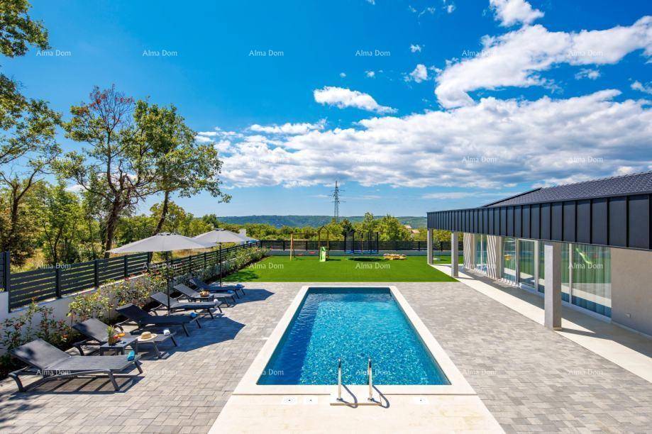 Weitläufiger Gartenbereich mit Swimmingpool, Liegestühlen und Kinderspielplatz vor grüner Landschaft.