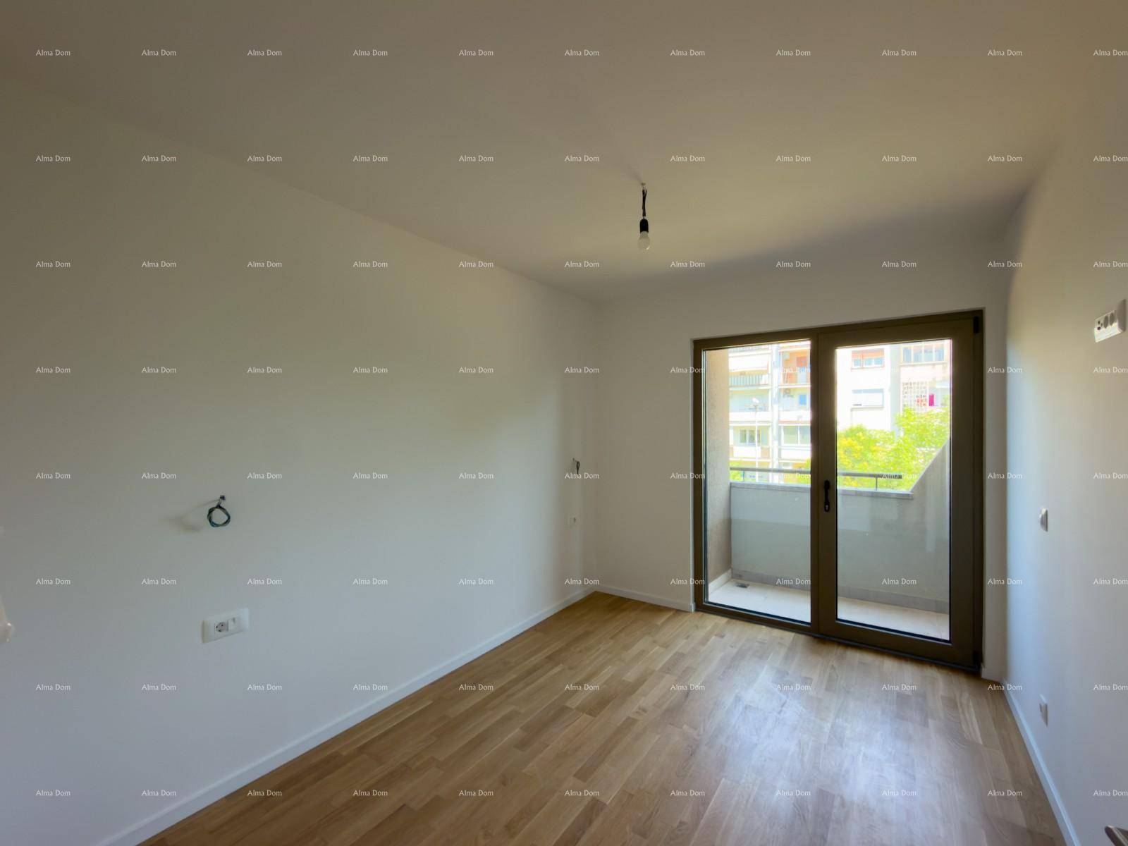 Helles Zimmer mit Holzboden und Balkonzugang, bietet eine angenehme Aussicht ins Grüne.