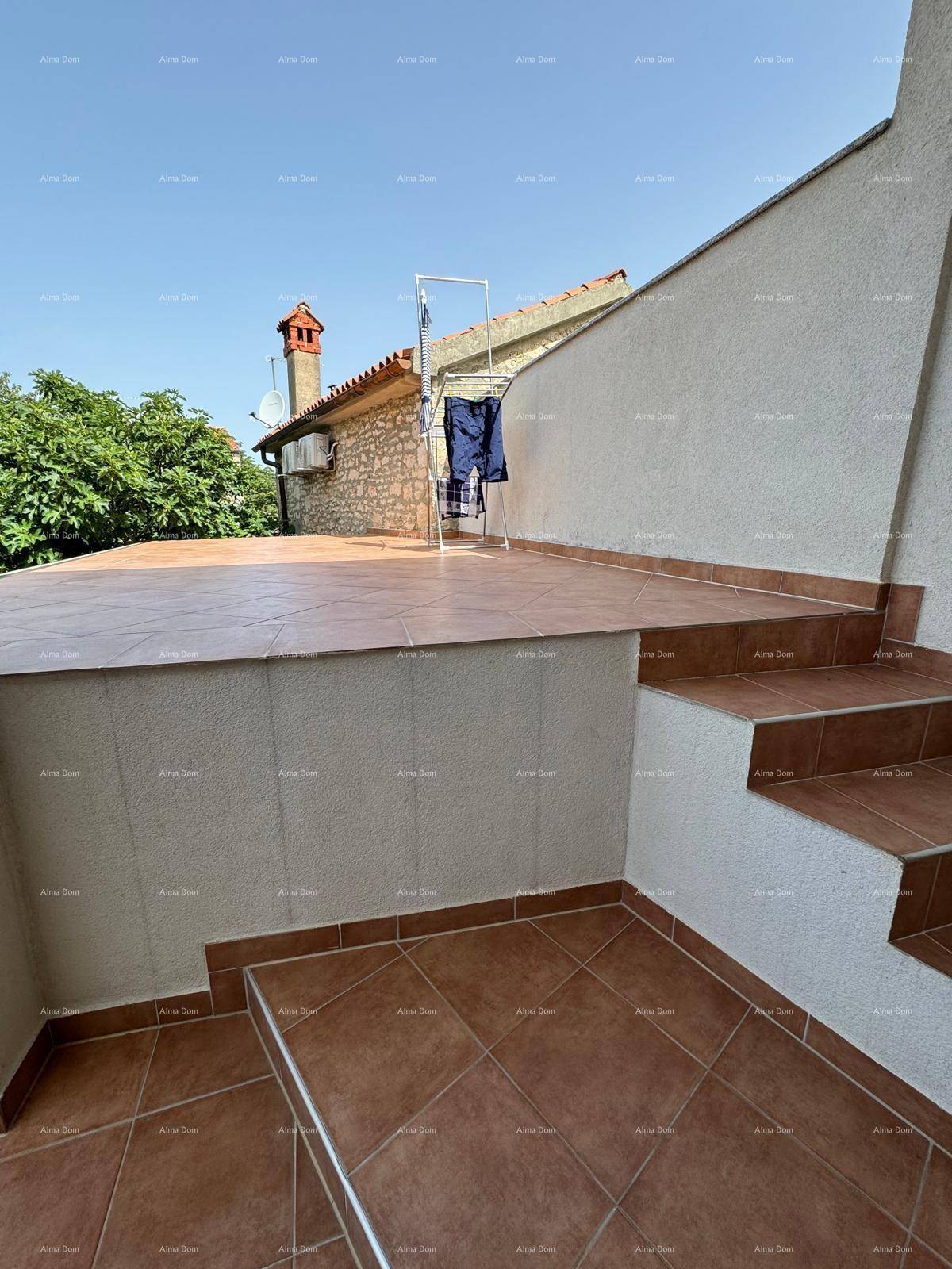 Obere Terrasse mit Wäscheständer und Blick auf das Dach eines benachbarten Gebäudes.