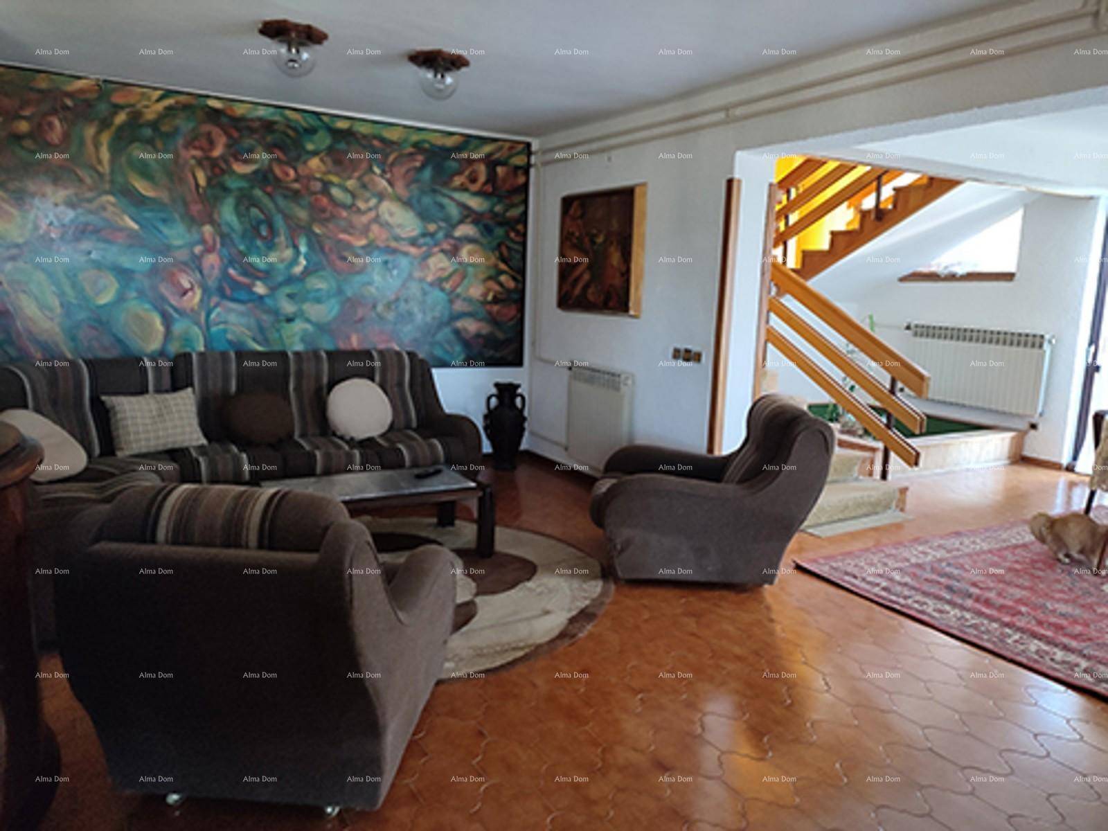Geräumiges Wohnzimmer mit großem Sofa, farbenfrohem Wandgemälde und Treppenaufgang.