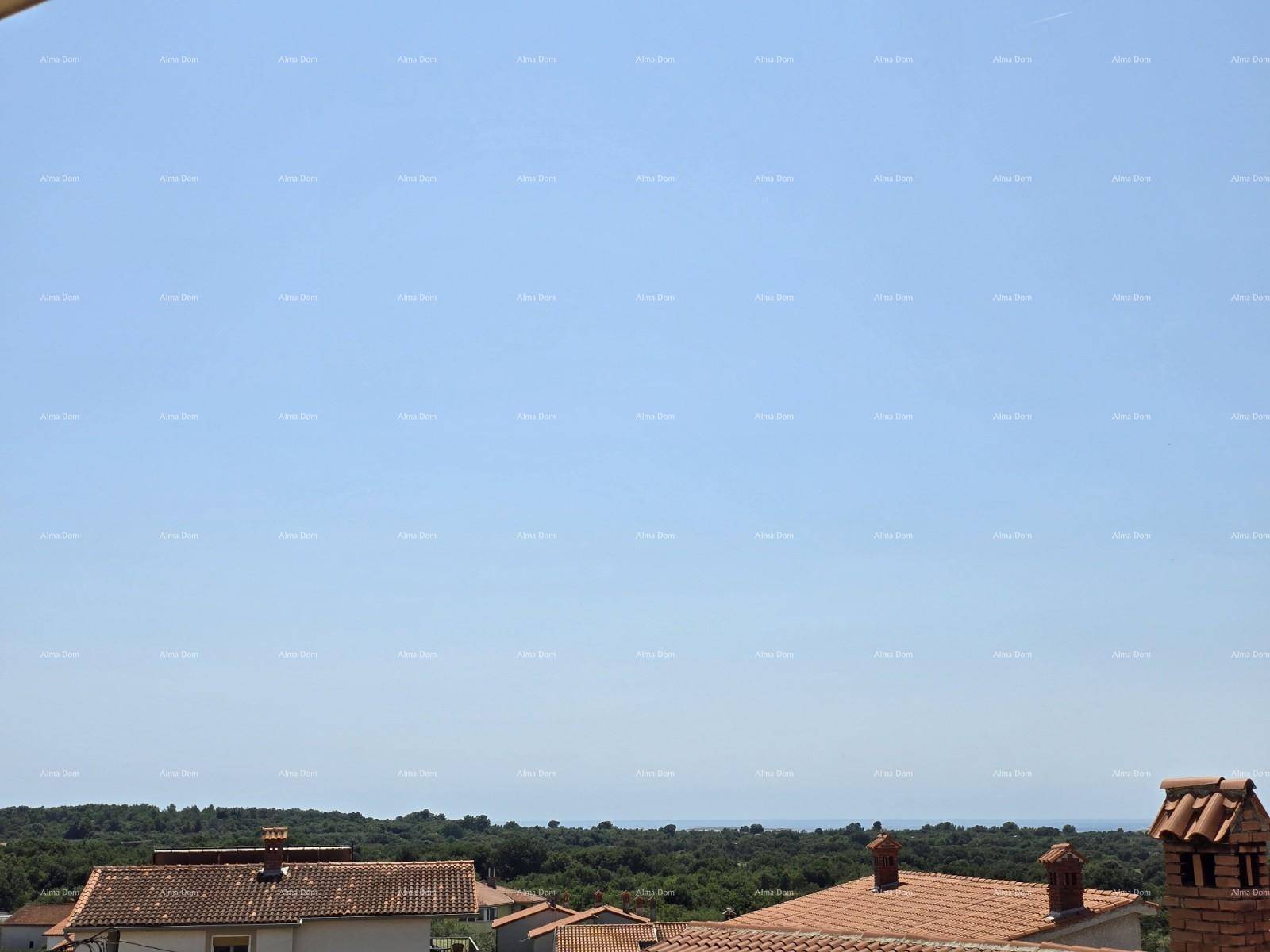 Weitblick über Dächer und grüne Baumwipfel bis zum Horizont mit dem Meer unter blauem Himmel.