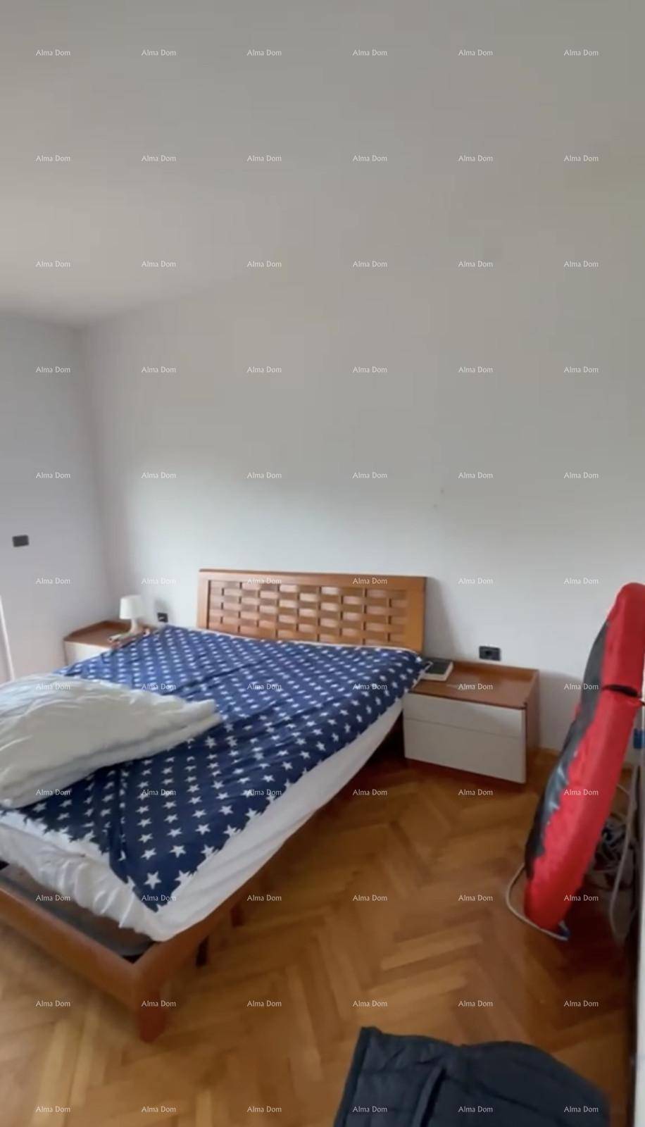Schlafzimmer mit Holzbett, blau-weiß gemusterter Bettwäsche und Fischgrätparkettboden.