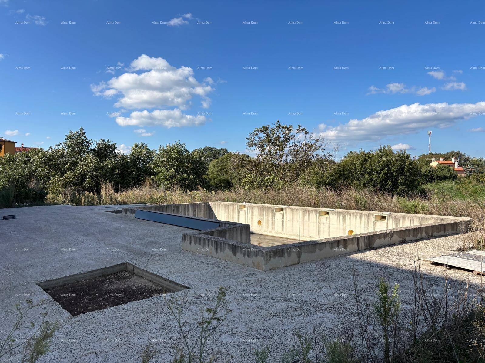 Rohbau des Pools in einer ländlichen Umgebung unter blauem Himmel mit weiten Feldern.