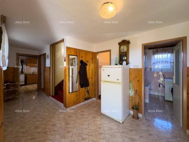 Flur mit Fliesenboden, Holzvertäfelung, einem Kühlschrank und Zugang zu weiteren Räumen.