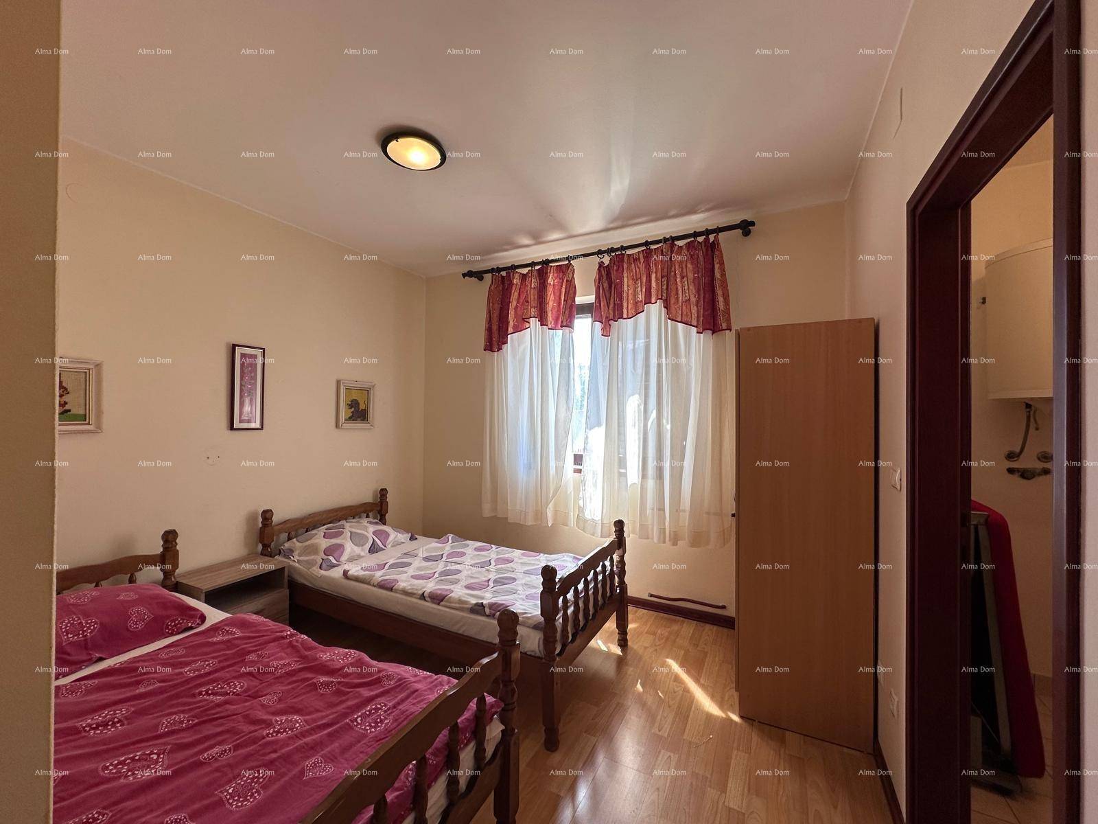 Schlafzimmer mit zwei Einzelbetten, Vorhängen und Holzboden, mit natürlichem Lichteinfall.