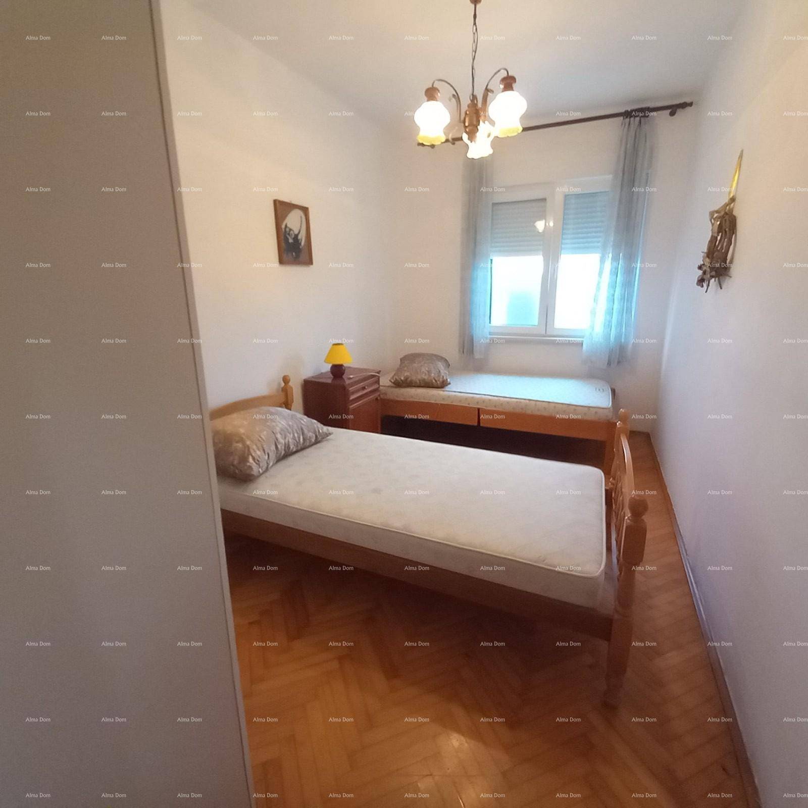 Schlafzimmer mit zwei Einzelbetten und Parkettboden, beleuchtet von einem klassischen Kronleuchter.