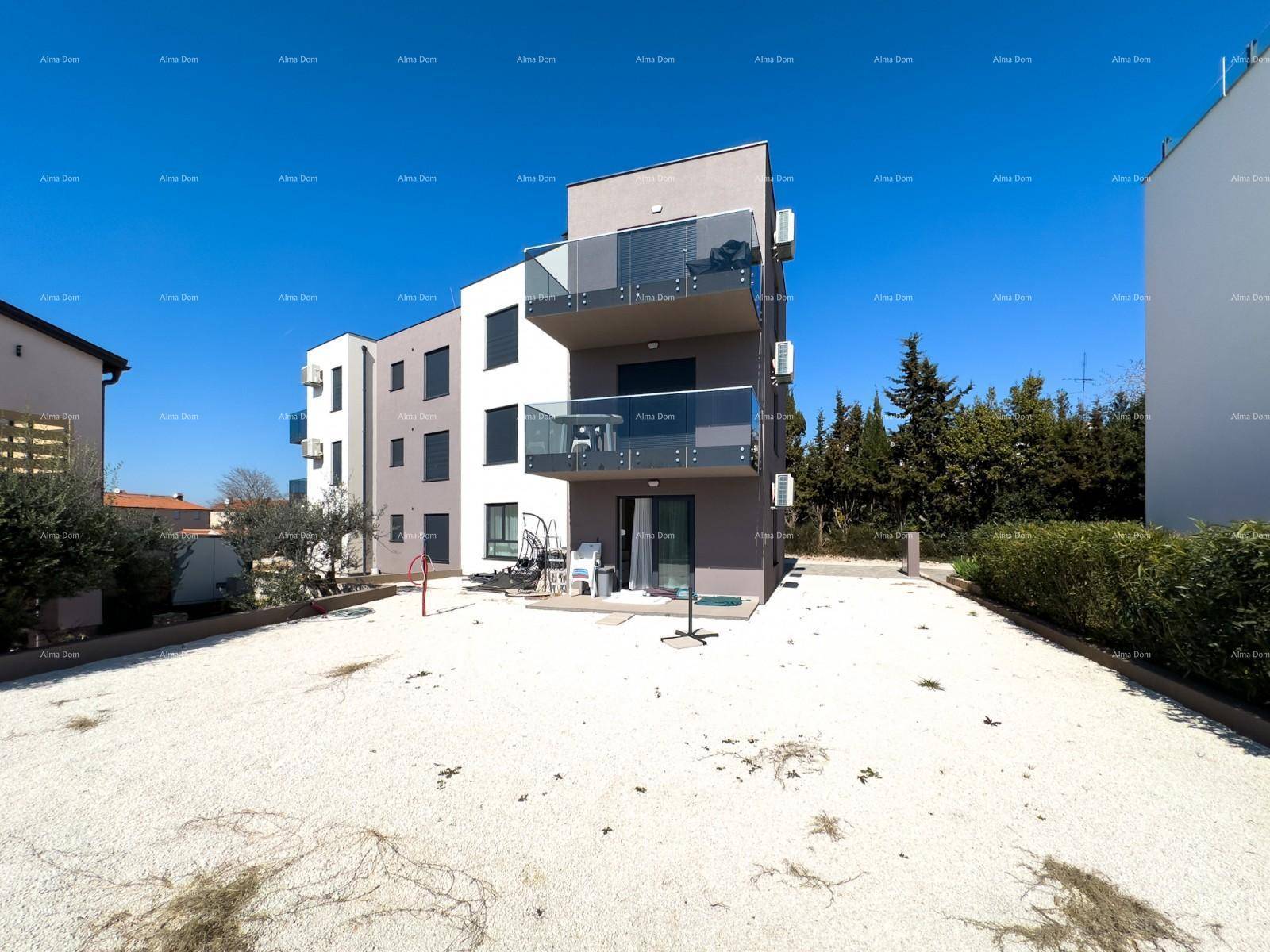 Modernes Mehrfamilienhaus mit Balkonen und einer weitläufigen Kiesfläche.