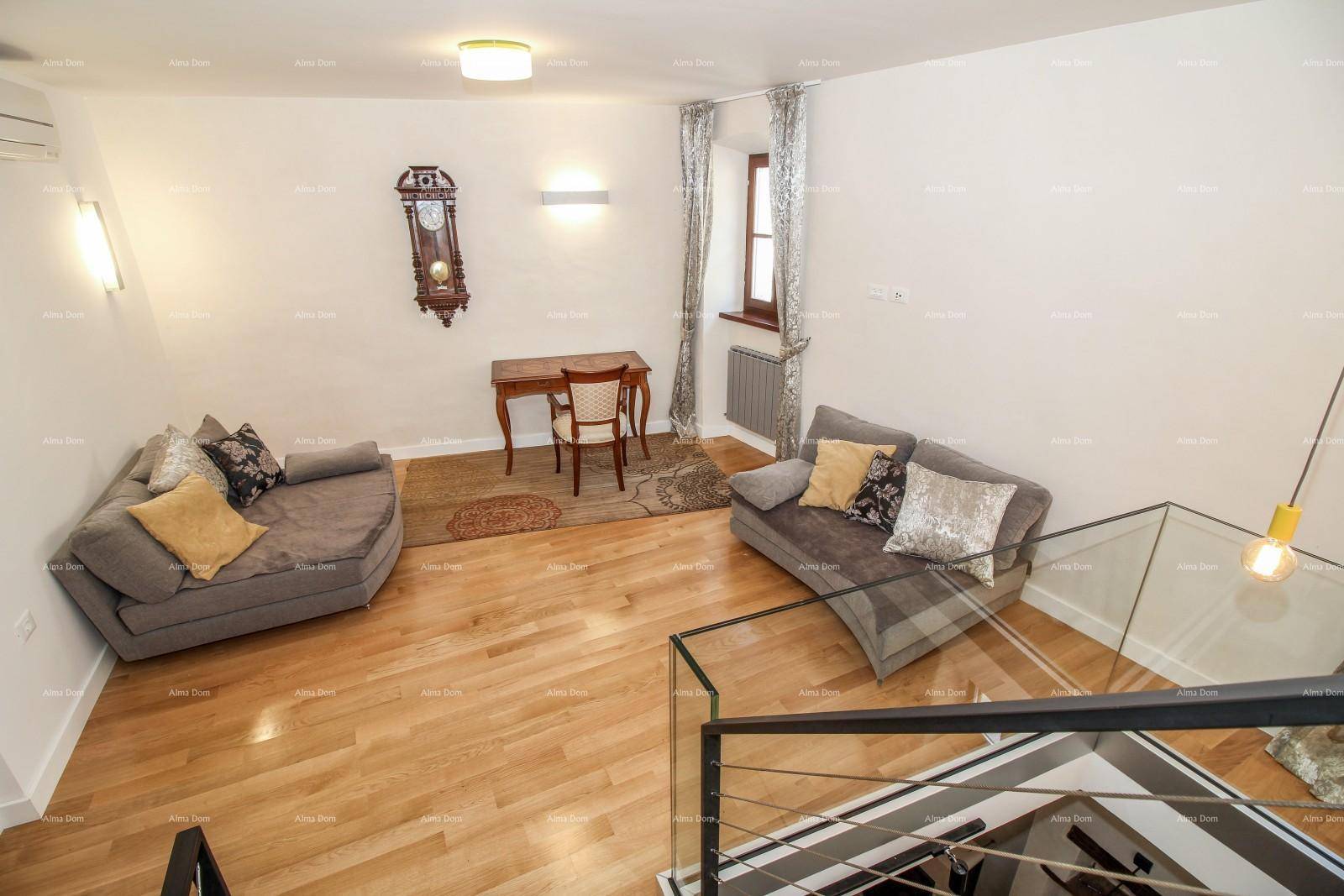Offener Wohnbereich mit Holzboden, zwei Sofas und einem Arbeitsplatz unter der Treppe.