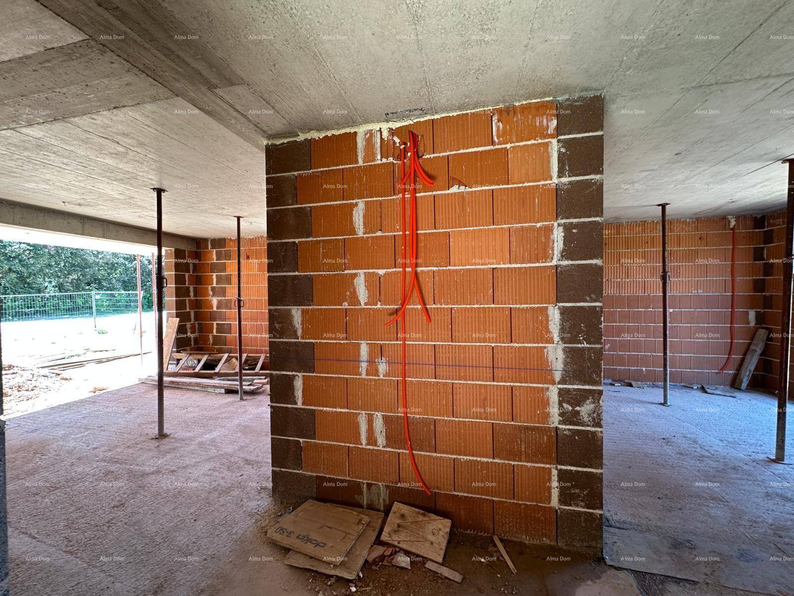 Rohbau-Innenraum mit Ziegelwänden, Betondecke und sichtbaren Elektroinstallationen an der Wand.