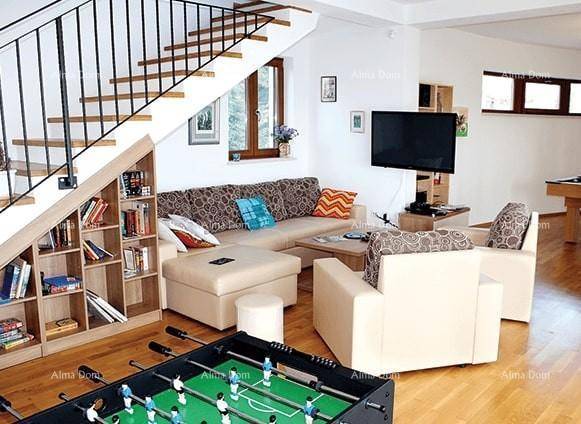 Gemütliches Wohnzimmer mit Treppe, integriertem Bücherregal und Unterhaltungsmöglichkeiten wie einem Kickertisch.