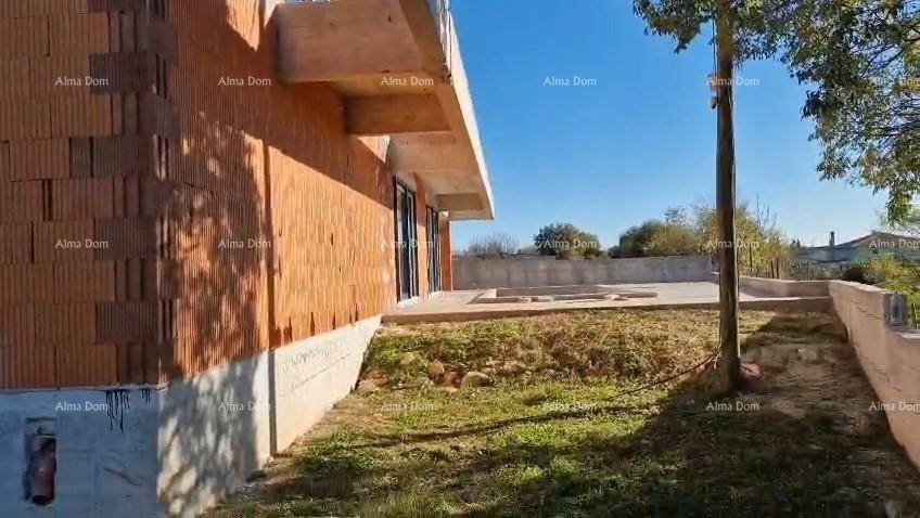 Rohbau des Hauses mit angrenzendem Gartenbereich und der zukünftigen Betonterrasse bei Sonnenschein.