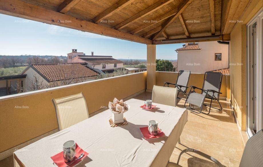Möblierter Balkon mit Holzdach und weitem Blick über die umliegende Landschaft.