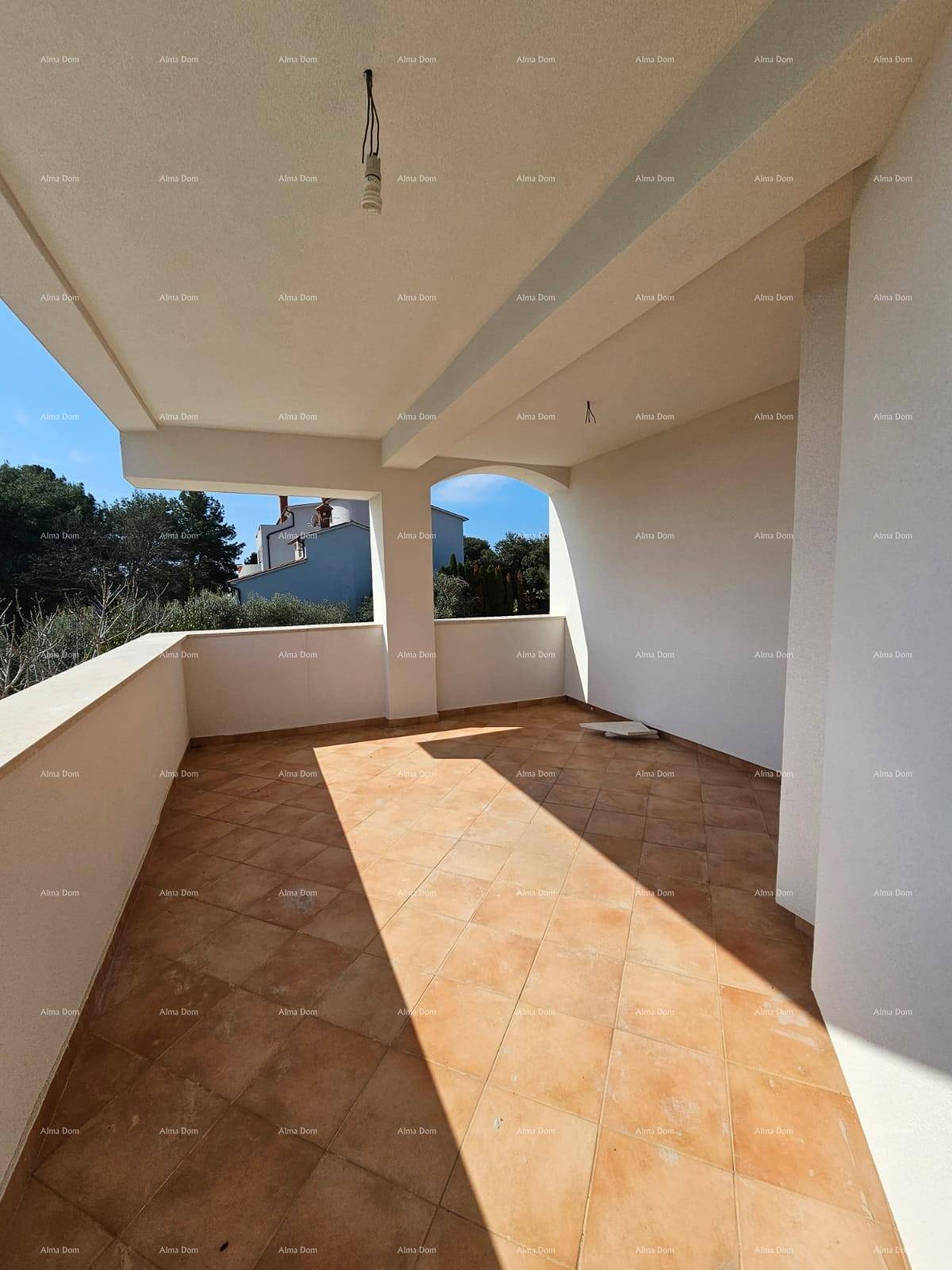 Großer überdachter Balkon mit Fliesenboden und Blick auf die Umgebung.