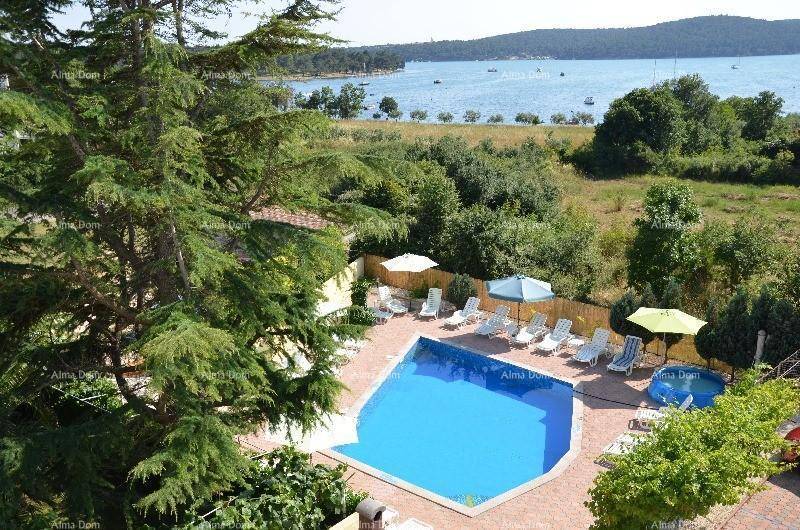 Weitläufiger Blick auf den Poolbereich, den Garten und das Meer in der Ferne.