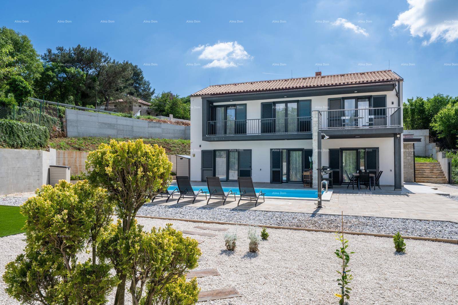 Modernes Wohnhaus mit Pool, Kiesgarten und grüner Umgebung an einem sonnigen Tag.