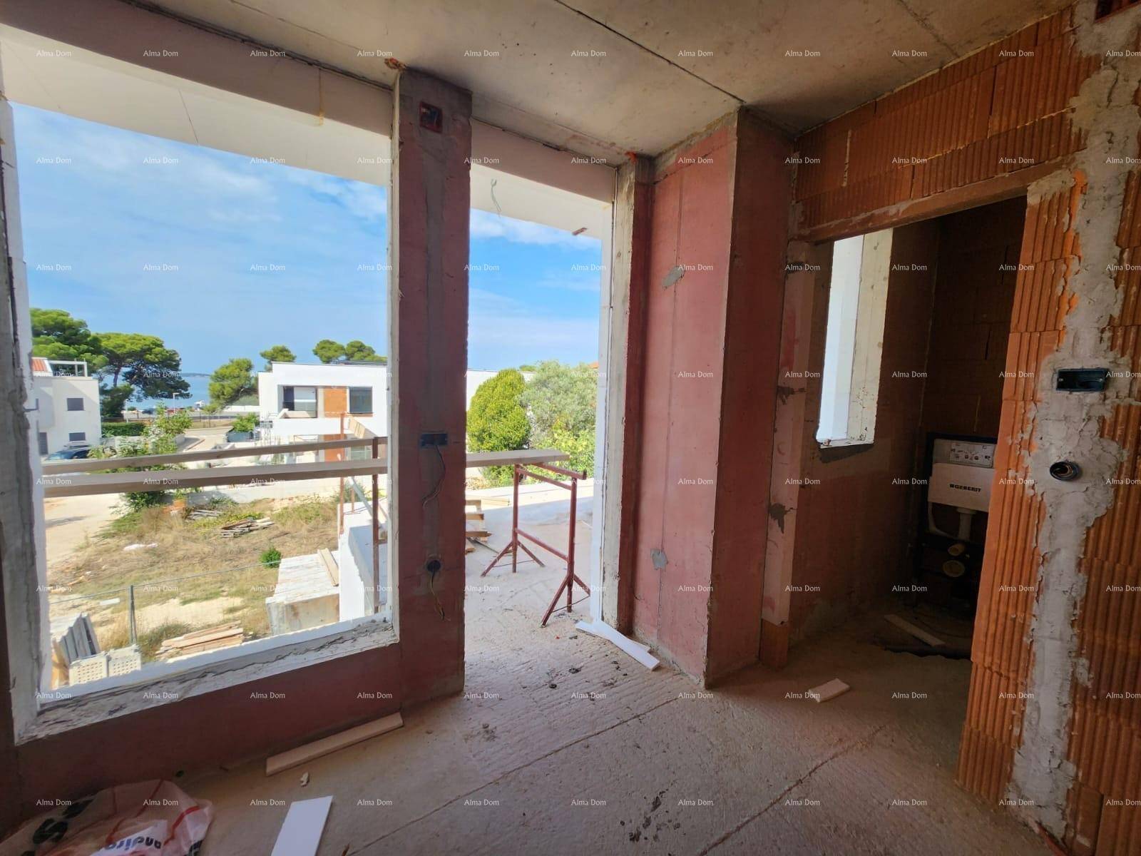 Rohbau eines Raumes mit großen Fensteröffnungen und Blick auf die Baustelle und das Meer.
