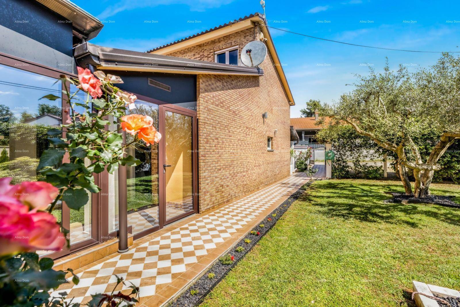 Rückseite des Hauses mit Ziegelmauerwerk, großen Glasflächen und einem grünen Rasenbereich.