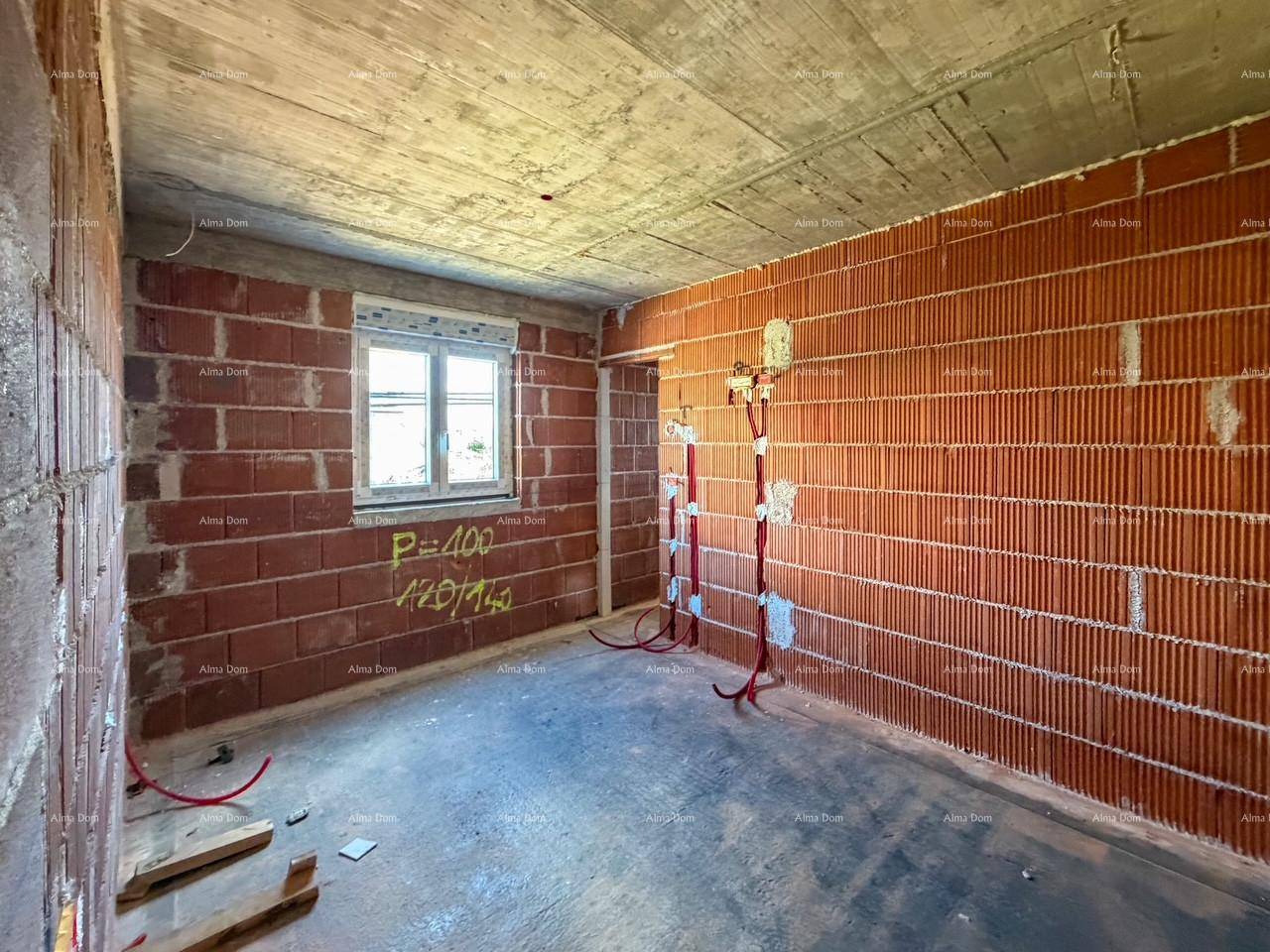 Raum im Rohbau mit Ziegelwänden, einem Fenster und sichtbaren Elektroinstallationen.