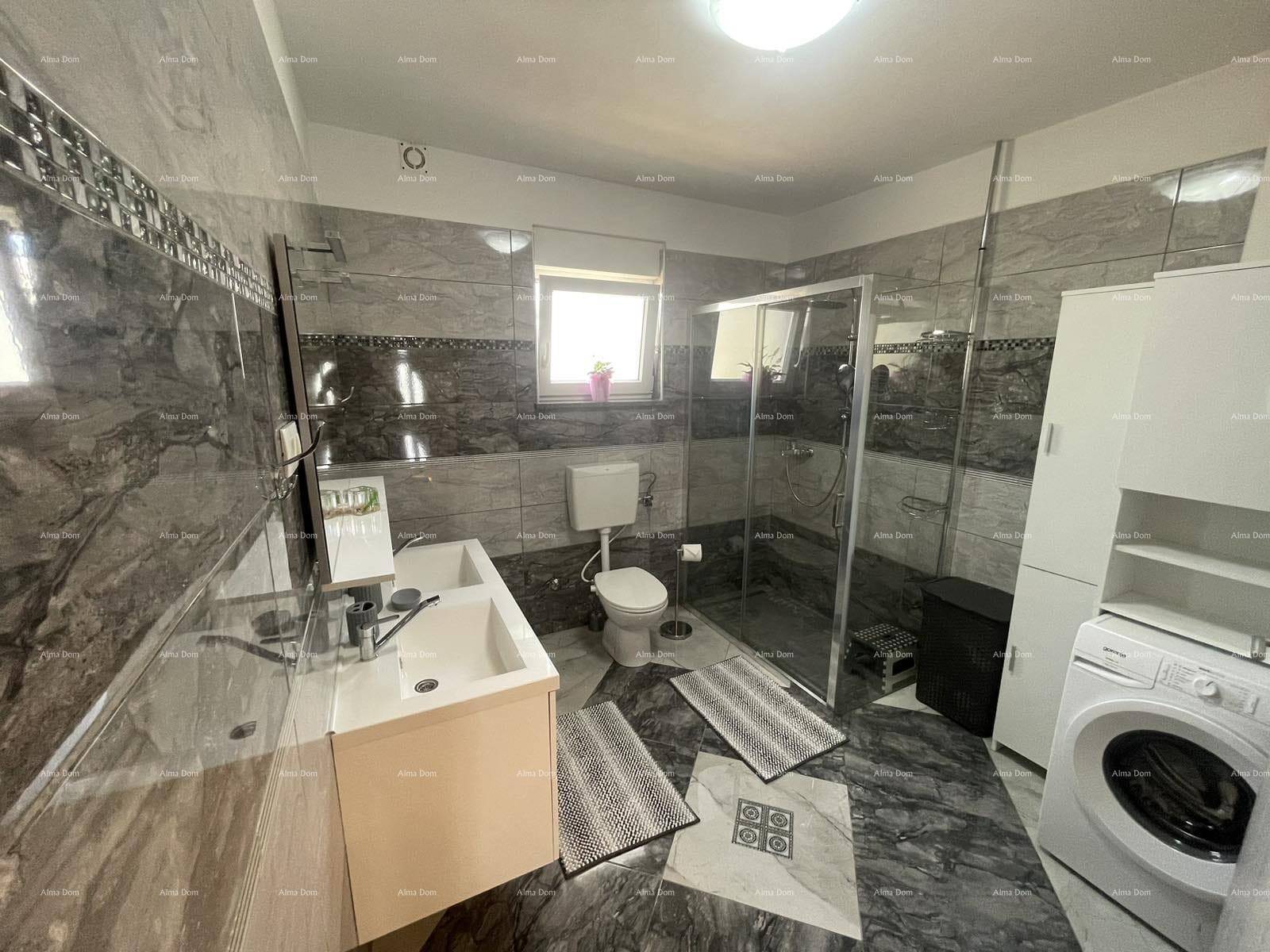 Geräumiges Badezimmer mit Duschkabine, Toilette, Waschmaschine und modernem Waschtisch mit Spiegel.