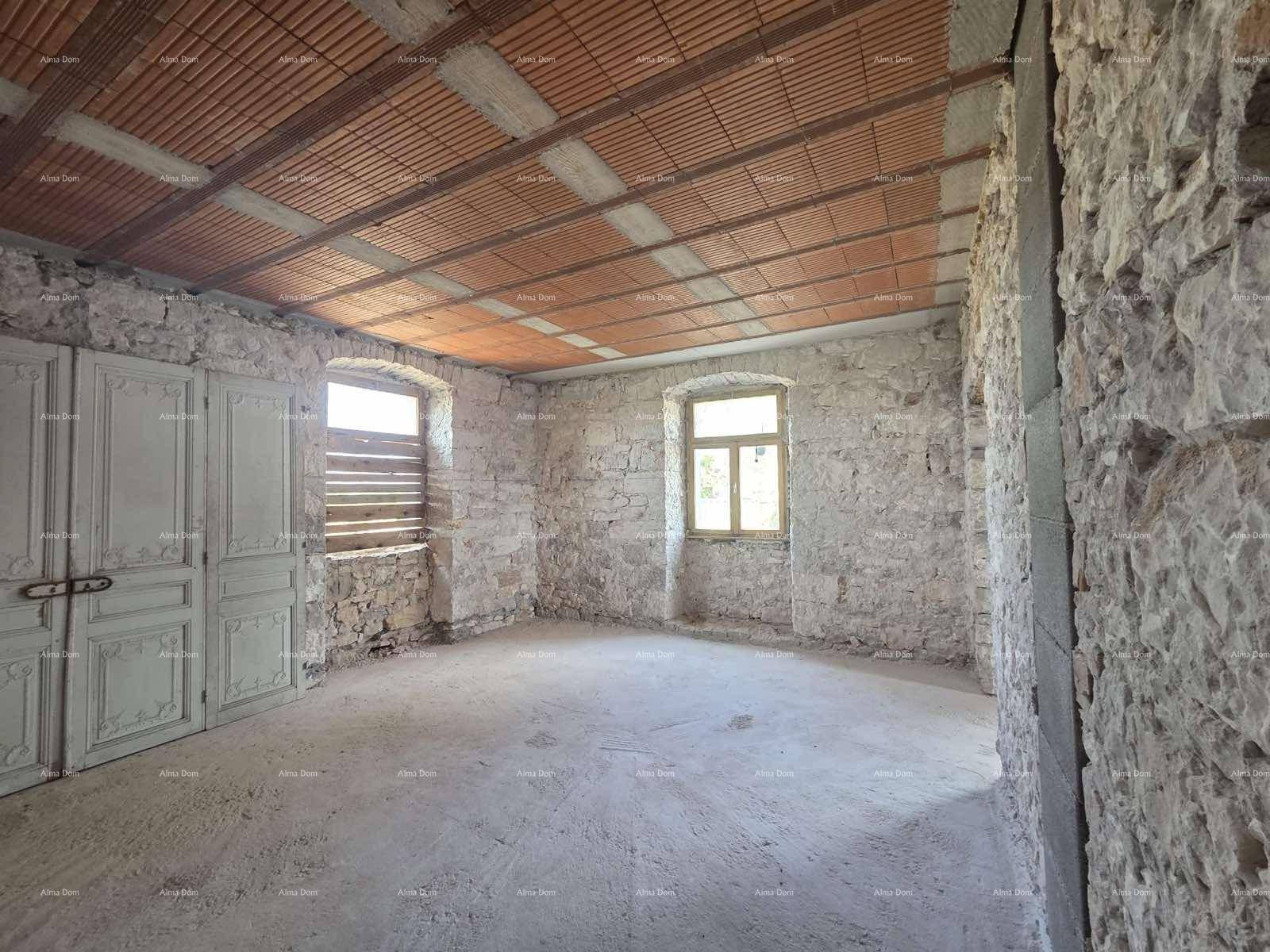 Raum im Rohbau mit freiliegenden Steinwänden, Ziegeldecke und Fenstern mit Holzläden.