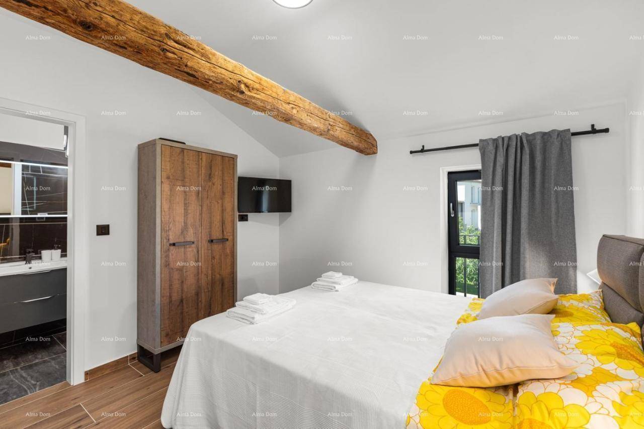 Gemütliches Schlafzimmer mit Doppelbett, Holzschrank und freiliegendem Holzbalken, mit Zugang zum Bad.