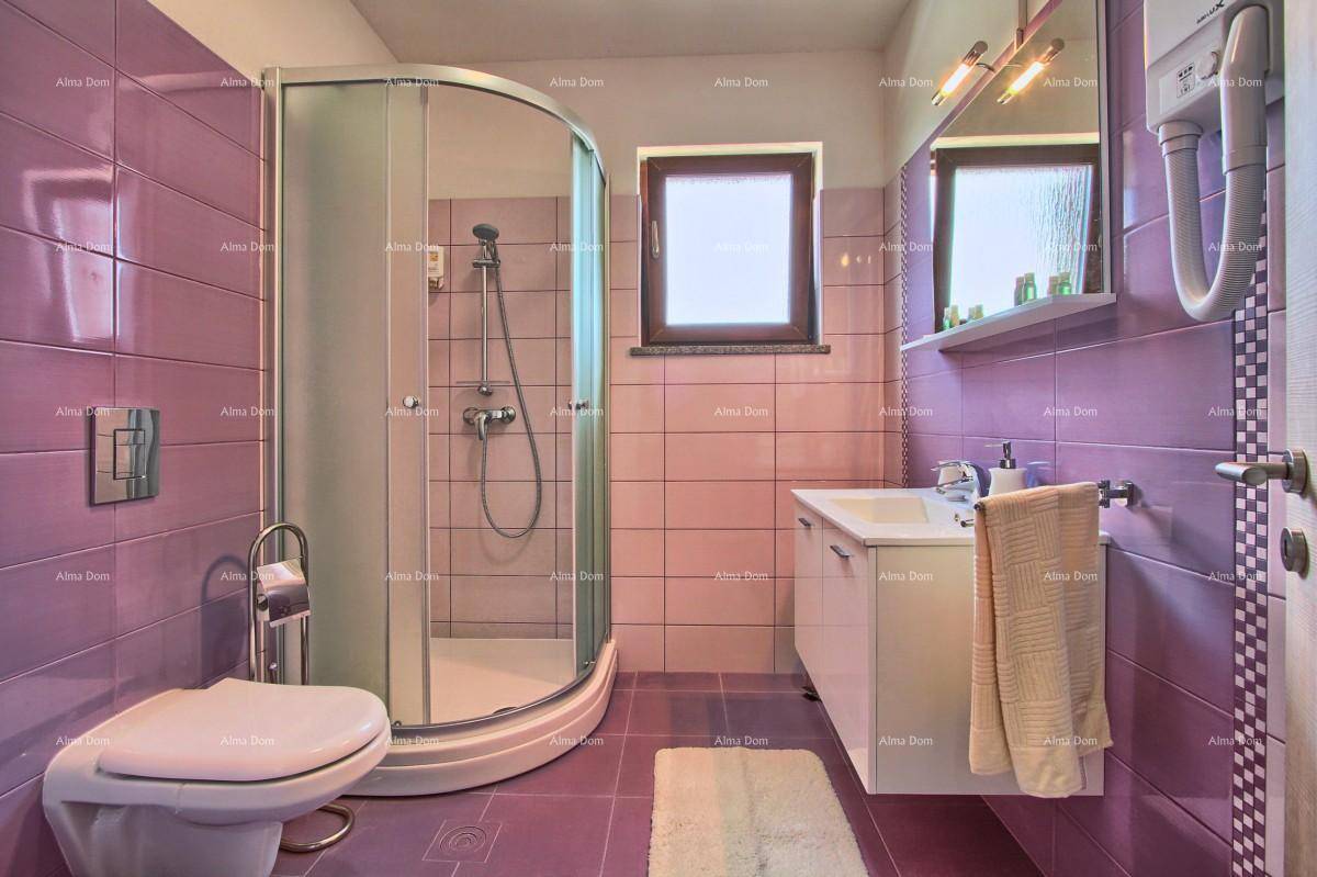 Badezimmer mit lila Fliesen, Eckduschkabine, Toilette und Fenster.