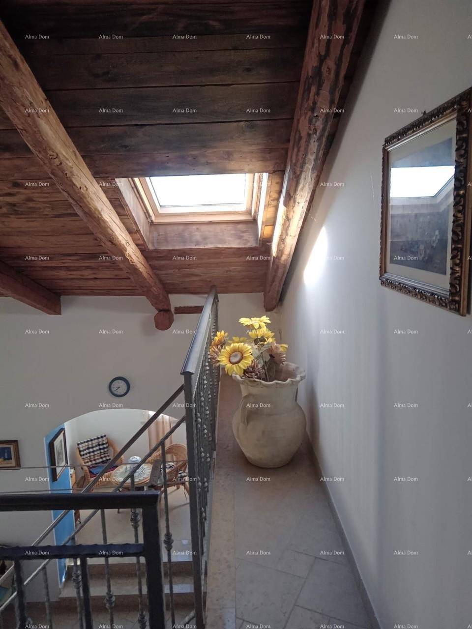 Heller Treppenabsatz mit Dachfenster, Holzbalken und dekorativer Vase.