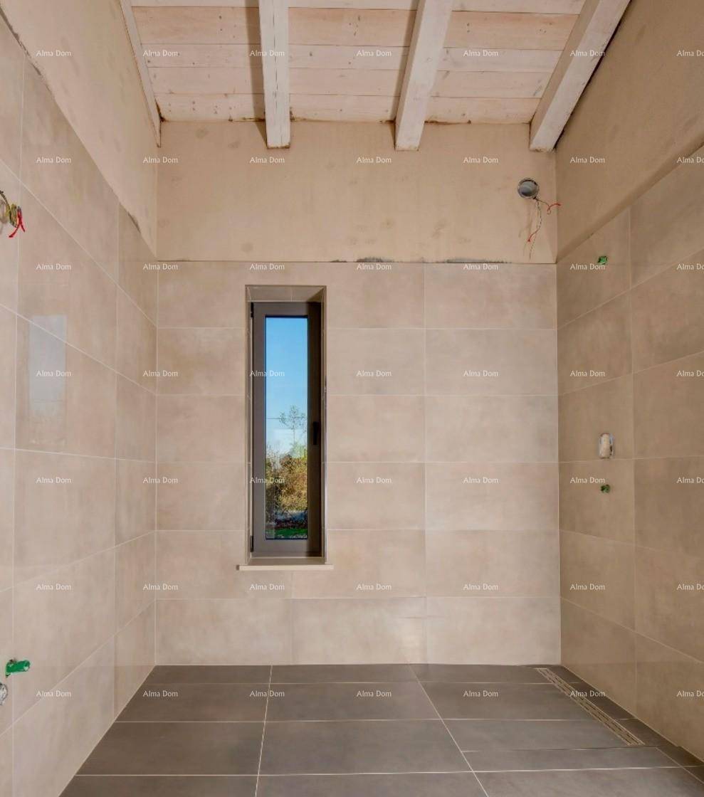 Badezimmer im Rohbau mit schmalem Fenster, beigefarbenen Wandfliesen und sichtbaren Deckenbalken.