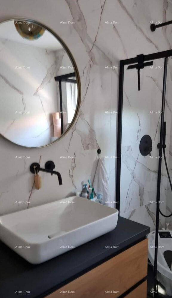Modernes Badezimmer mit Marmorfliesen, rundem Spiegel und schwarzer Armatur am Waschbecken.