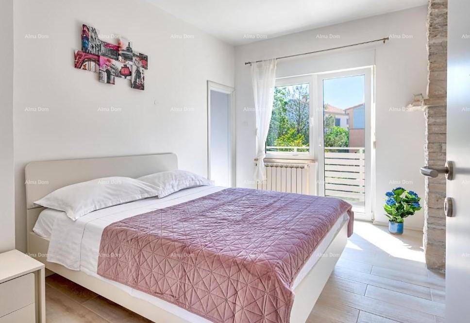 Schlafzimmer mit Doppelbett, Holzboden und Zugang zu einem kleinen Balkon.