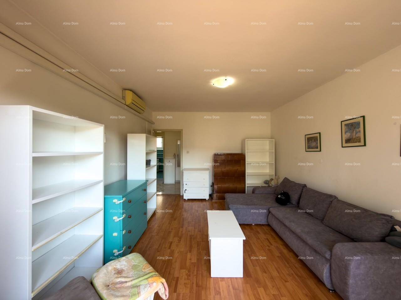 Wohnzimmer mit Holzfußboden, Klimaanlage und Blick auf die Regale und Couch.