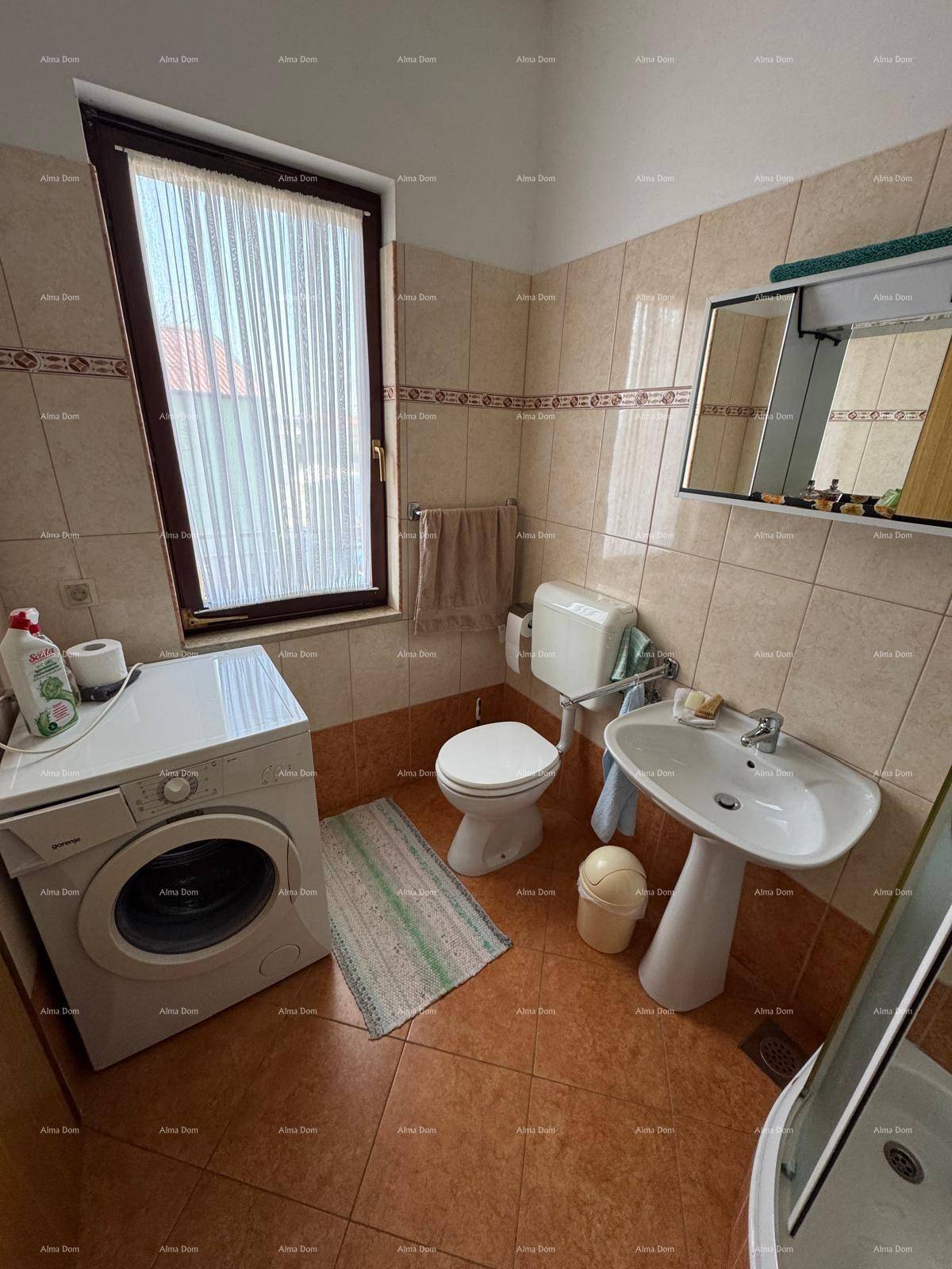 Badezimmer mit Waschmaschine, Toilette, Waschbecken und Fenster, in warmen Farbtönen.